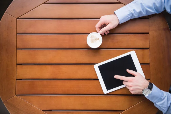 Imagen recortada del hombre usando la tableta y sosteniendo la taza de café - foto de stock