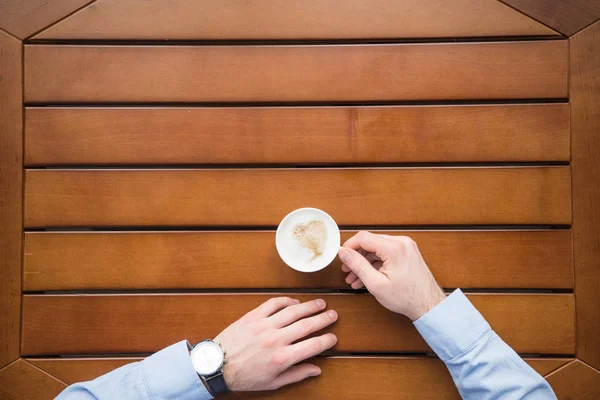 Обрізане зображення людини, що сидить за столом з чашкою кави — стокове фото