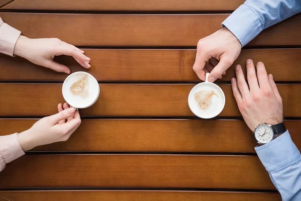 Imagem cortada de homem e mulher sentados à mesa com café — Fotografia de Stock