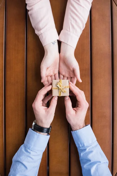 Cropped image of girlfriend gifting present box to boyfriend — Stock Photo
