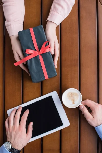 Immagine ritagliata di fidanzata regalo regalo scatola al fidanzato con tablet e caffè — Foto stock