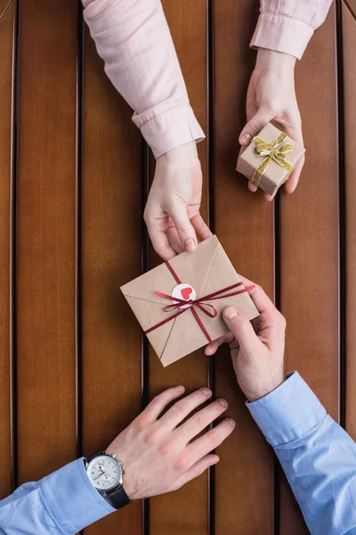 Cropped image of girlfriend gifting postcard in envelope and present box to boyfriend — Stock Photo