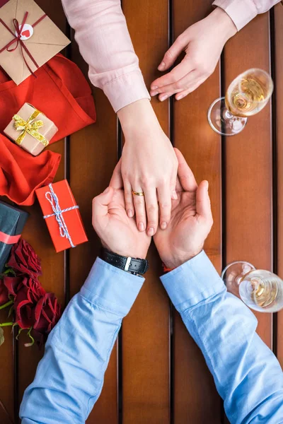 Cropped image of boyfriend holding girlfriends hand with wedding ring — Stock Photo