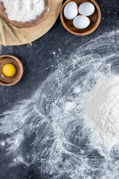 Puesta plana con harina, huevos crudos, yema y platos de madera sobre la mesa - foto de stock