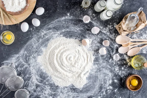 Deitado plano com farinha e outros ingredientes para padaria, utensílios de cozinha de madeira na mesa escura — Fotografia de Stock