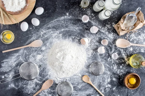 Плоская укладка с мукой и другими ингредиентами для пекарни, деревянные кухонные принадлежности на темной столешнице — стоковое фото