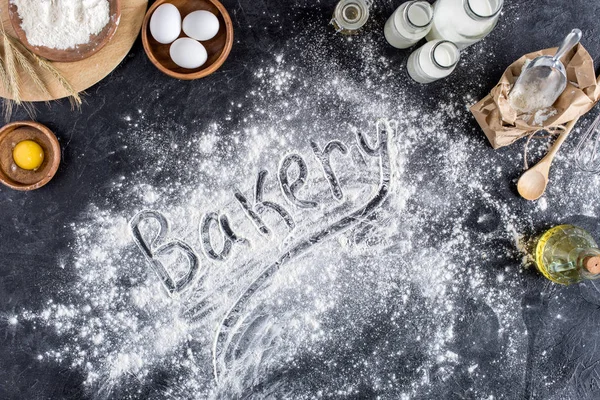 Top view of bakery lettering made of flour and various ingredients for baking on dark surface — Stock Photo