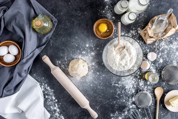 Top view of raw dough, baking ingredients and cutlery on marble surface — Stock Photo