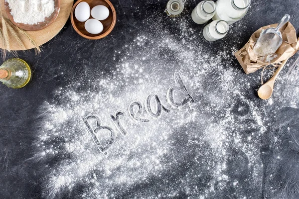 Top view of bread lettering made of flour and various ingredients for baking on dark surface — Stock Photo