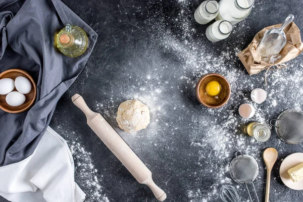 Top view of raw dough, baking ingredients and cutlery on marble surface — Stock Photo
