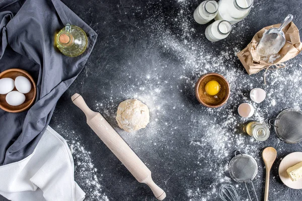 Vue du dessus de la pâte crue, des ingrédients de cuisson et des couverts sur la surface du marbre — Photo de stock