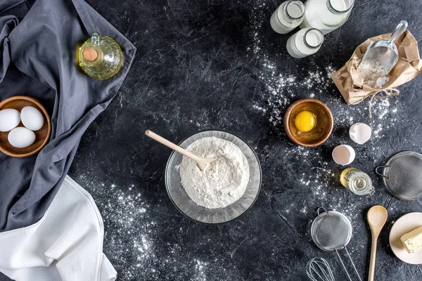 Vista superior de utensílios de cozinha dispostos e ingredientes para panificação na superfície de mármore escuro — Fotografia de Stock