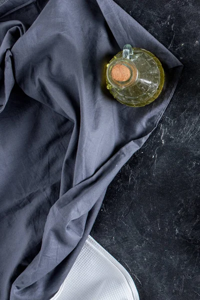Vista dall'alto di bottiglia di olio e tovaglia su tavolo in marmo scuro — Foto stock