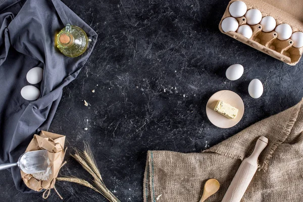 Pose plate avec divers ingrédients pour la cuisson du pain et des couverts sur la surface de marbre foncé — Photo de stock