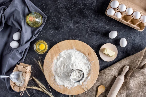 Flat lay with various ingredients for bread baking and cutlery on dark marble surface — Stock Photo