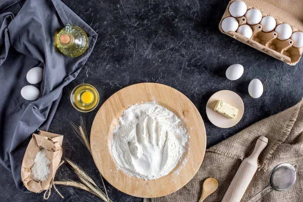 Flat lay with various ingredients for bread baking and cutlery on dark marble surface — Stock Photo