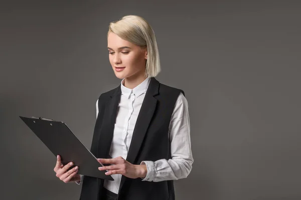 Portrait of stylish businesswoman with notepad isolated on grey — Stock Photo