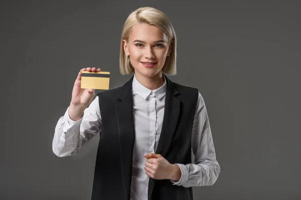 Portrait of smiling woman showing credit card in hand isolated on grey — Stock Photo