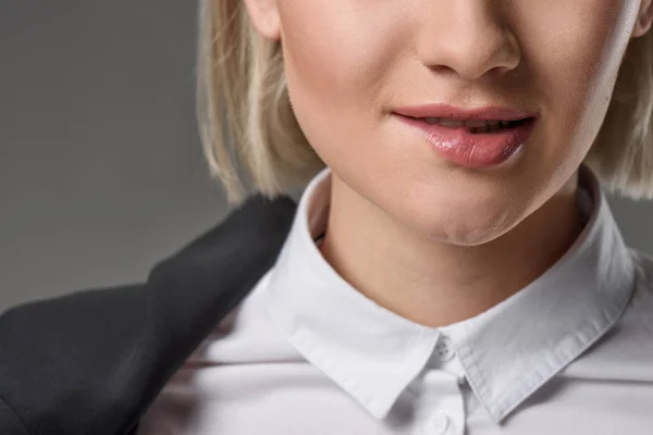 Обрізаний знімок жінки в білій сорочці кусає губу ізольовано на сірому — стокове фото