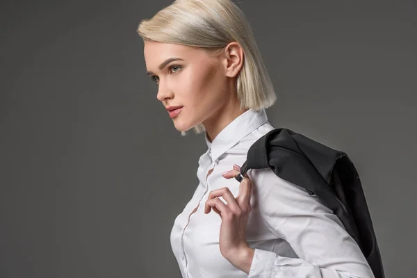 Seitenansicht einer stilvollen jungen Frau in weißem Hemd, die isoliert auf grau posiert — Stockfoto
