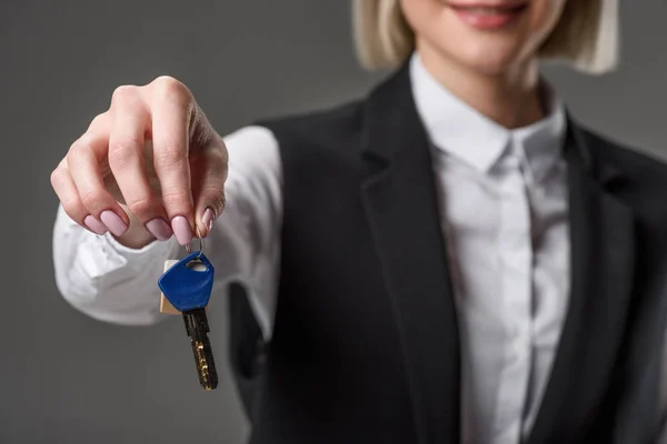 Plano recortado de la mujer de negocios que muestra las llaves de la casa en la mano aislado en gris - foto de stock