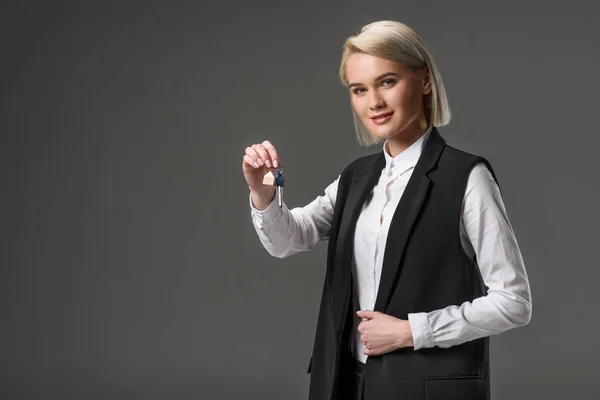 Portrait of real estate agent with keys in hand isolated on grey — Stock Photo