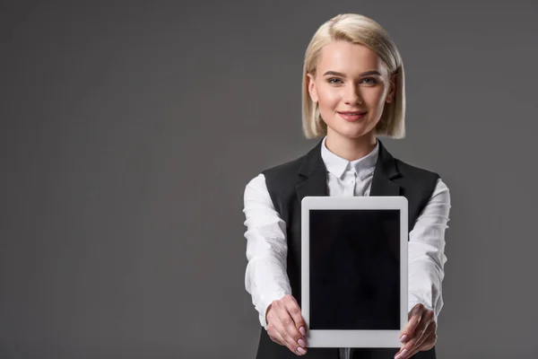 Portrait de femme souriante montrant une tablette avec écran blanc isolé sur gris — Photo de stock
