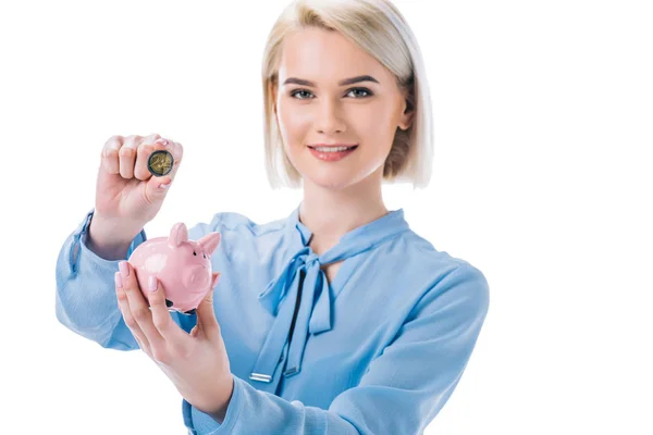 Ritratto di donna d'affari sorridente con salvadanaio e moneta in mano isolata su bianco — Foto stock