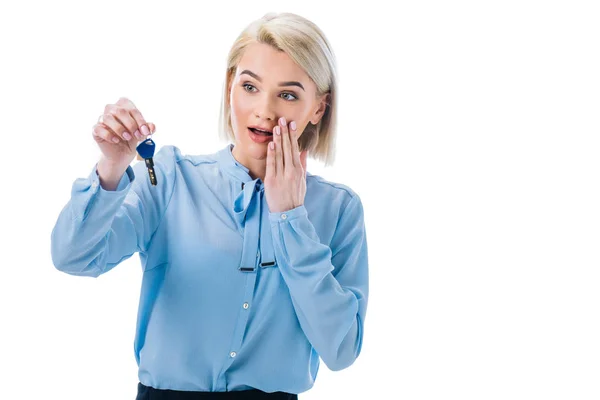 Mujer sorprendida sosteniendo la llave de nuevo hogar, aislado en blanco — Stock Photo