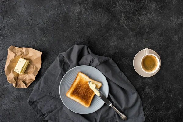 Vista dall'alto di pane tostato, burro e tazza di caffè per la prima colazione sulla superficie scura — Foto stock