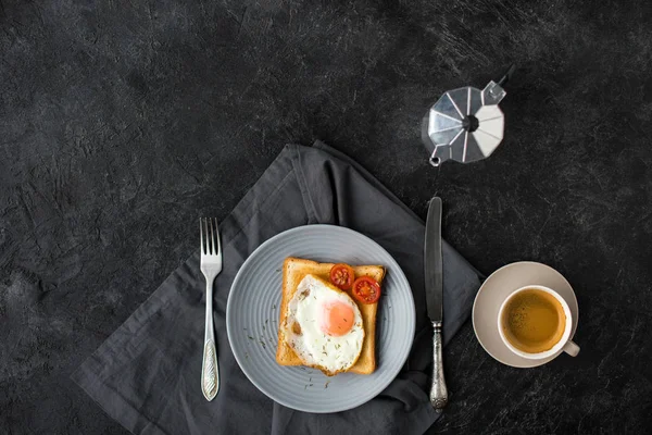 Acostado plano con taza de café y tostadas con huevo frito y tomates cherry para el desayuno en la superficie oscura - foto de stock