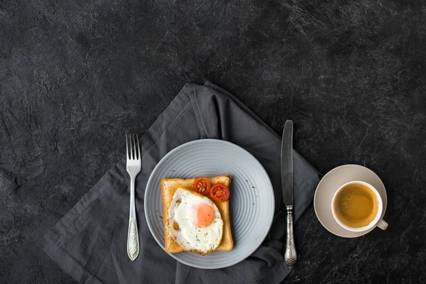 Flat lay com xícara de café e torrada com ovo frito e tomate cereja para o café da manhã na superfície escura — Fotografia de Stock