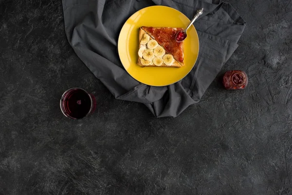 Vue de dessus des toasts avec des tranches de banane et de la confiture pour le petit déjeuner sur la table sombre — Photo de stock