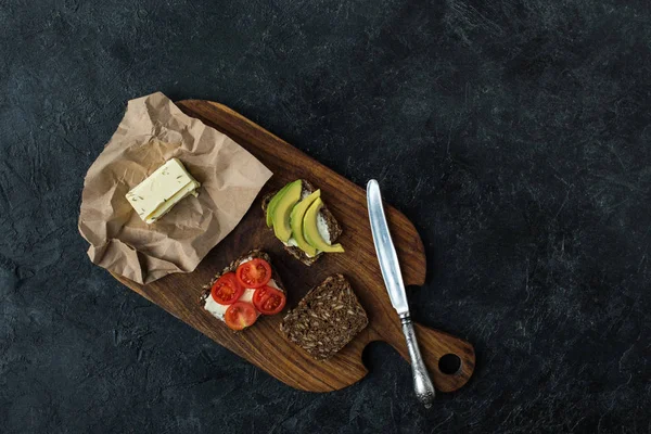 Flache Liege mit Snacks für ein gesundes Frühstück auf Holzschneidebrett auf dunkler Tischplatte — Stockfoto