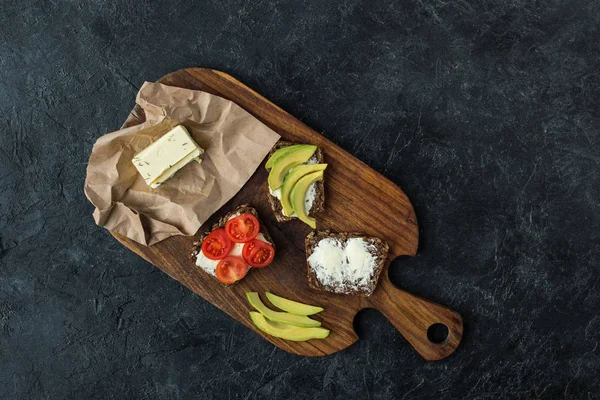 Flat lay com lanches para o café da manhã saudável na tábua de corte de madeira na mesa escura — Fotografia de Stock