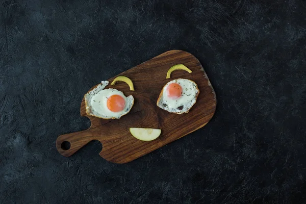 Vista superior de la cara sonriente hecha de comida para un desayuno saludable en la tabla de cortar - foto de stock