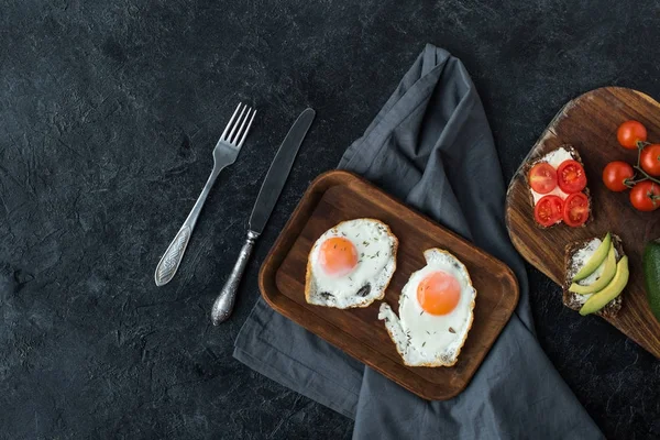 Vista superior de huevos fritos y bocadillos saludables para el desayuno en la mesa oscura - foto de stock