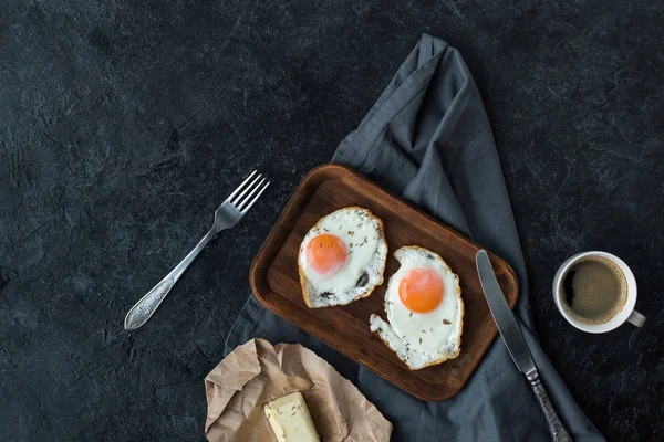 Вид зверху на смажені яйця, масло і чашку кави на сніданок на темній стільниці — стокове фото