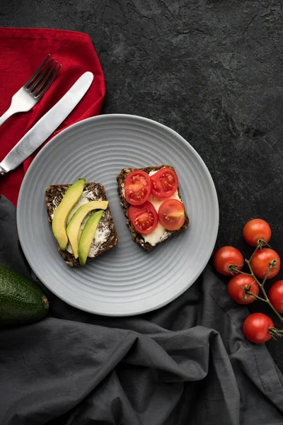 Vista superior de desayuno saludable y tomates cherry en la superficie oscura - foto de stock