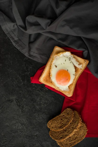 Vista superior del huevo frito en tostadas y rebanadas de pan en la superficie oscura - foto de stock