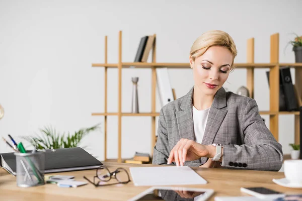 Ritratto della donna d'affari che controlla l'ora sul posto di lavoro in ufficio — Foto stock