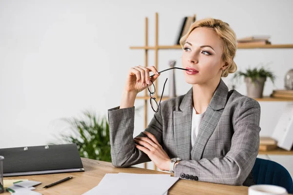 Porträt einer nachdenklichen Geschäftsfrau mit Brille, die am Arbeitsplatz wegschaut — Stockfoto