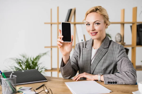 Retrato de mulher de negócios sorridente mostrando smartphone com tela em branco na mão — Fotografia de Stock