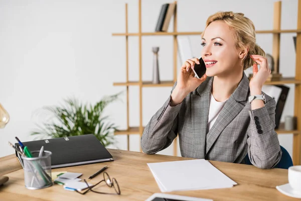 Donna d'affari sorridente che parla su smartphone sul posto di lavoro in ufficio — Foto stock