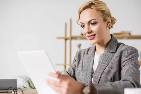 Mujer de negocios sonriente con tableta digital en el lugar de trabajo en la oficina - foto de stock