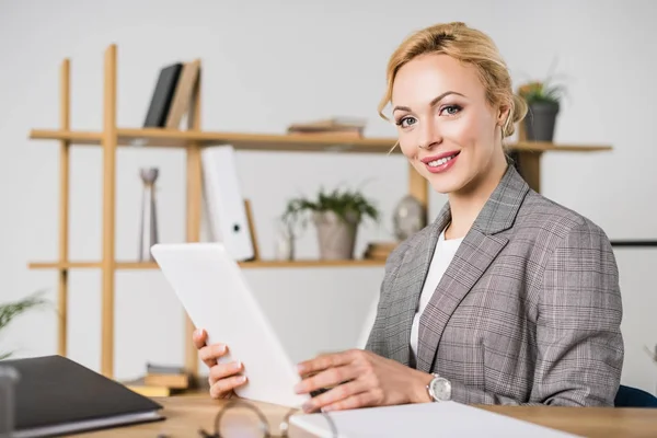 Retrato de atractiva mujer de negocios con tableta sentada en el lugar de trabajo - foto de stock