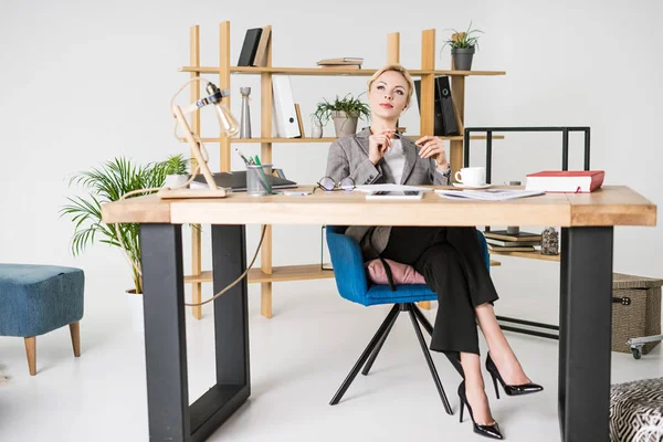 Donna d'affari pensierosa che guarda lontano al posto di lavoro in ufficio — Foto stock