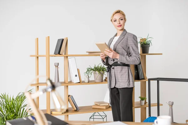 Empresária confiante em terno com notebook em pé no escritório — Fotografia de Stock