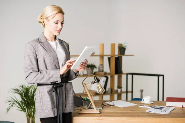 Портрет впевненої бізнес-леді, що використовує планшет, стоячи на робочому місці в офісі — стокове фото