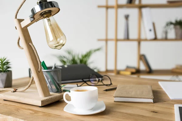 Close up view of cup of coffee and notebook at workplace — Stock Photo